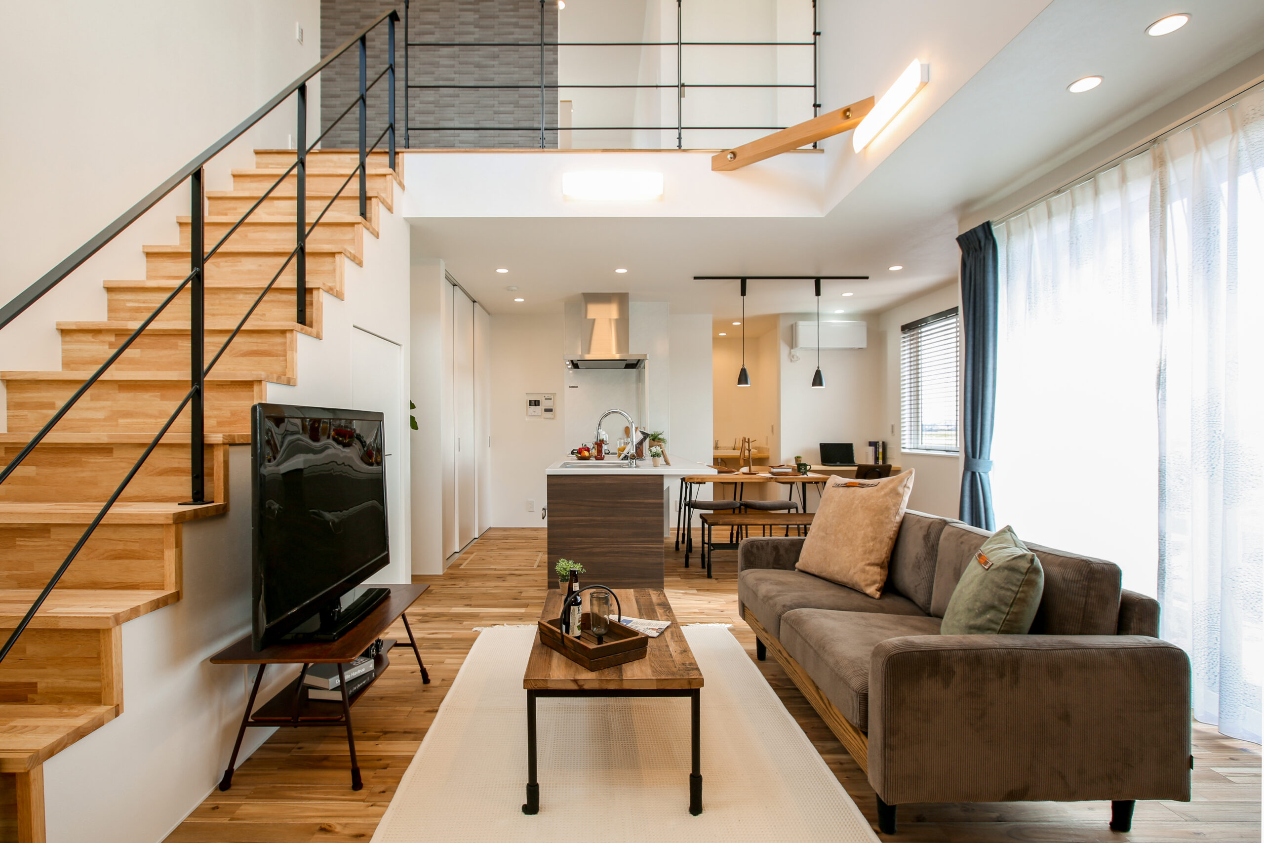 吹き抜けから光が広がる明るい住まい。開放的なリビングと自然素材を使った心地よい空間が広がる家。