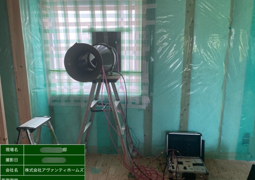 気密測定の現場写真。送風機と測定機器を使用して新築住宅のC値（隙間相当面積）を測定している様子。
